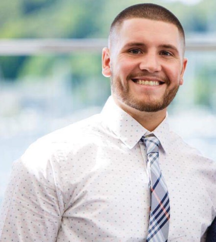 a man wearing a suit and tie smiling at the camera